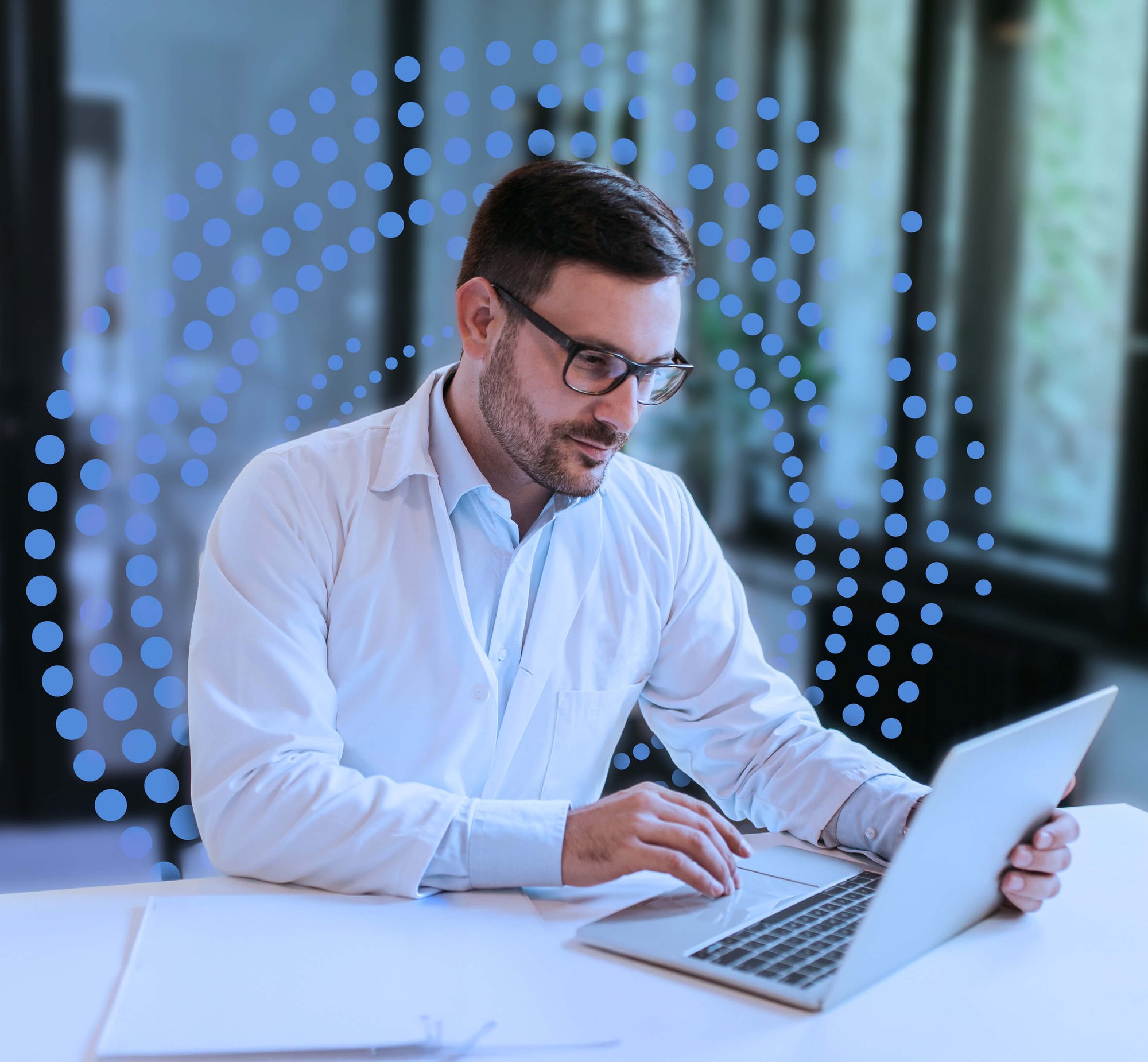 Doctor working in his office on a laptop, with blue dots in the background